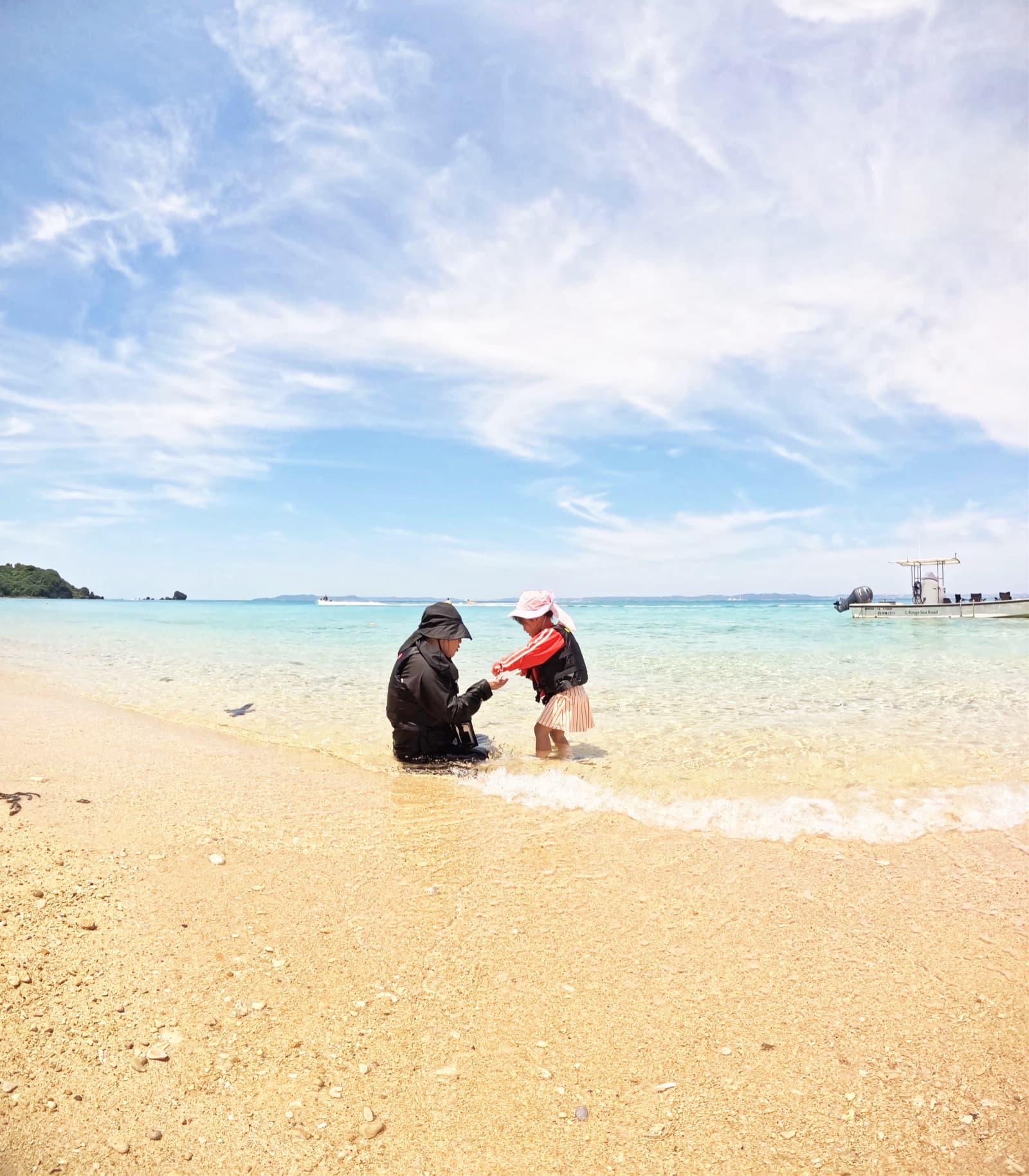 Family playing in calm shallows of an uninhabited island in Okinawa