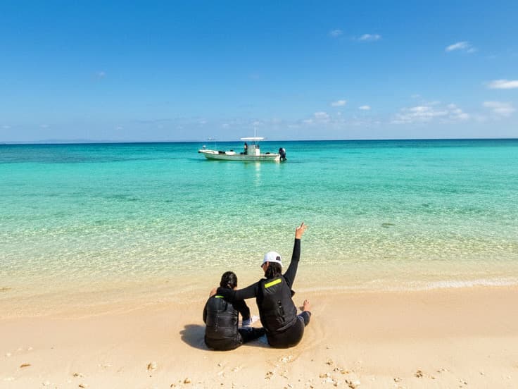 沖縄・浜比嘉島の無人島でくつろぐカップルとKingsSeaRoadのボート